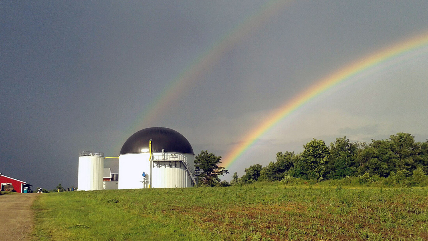 anaerobic digester on a dairy farm with rainbow in background