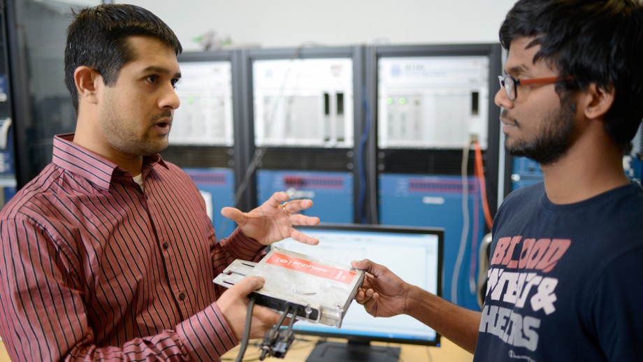 FREEDM Center staff member advising student on energy-related research while holding an electrical component